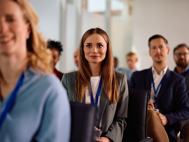 Persona con acreditación sentada entre el público de una sala de conferencias
