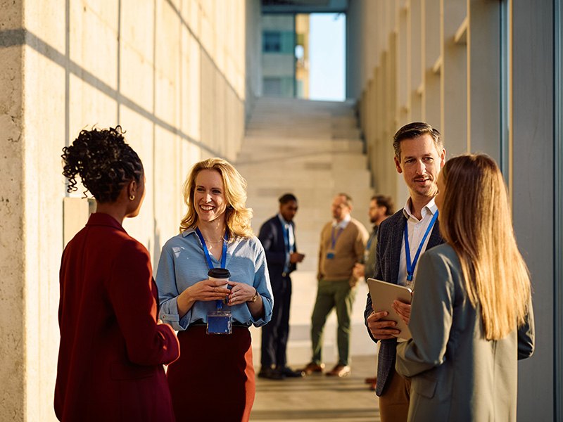 Grupo de profesionales conversando en el pasillo de un centro de congresos.