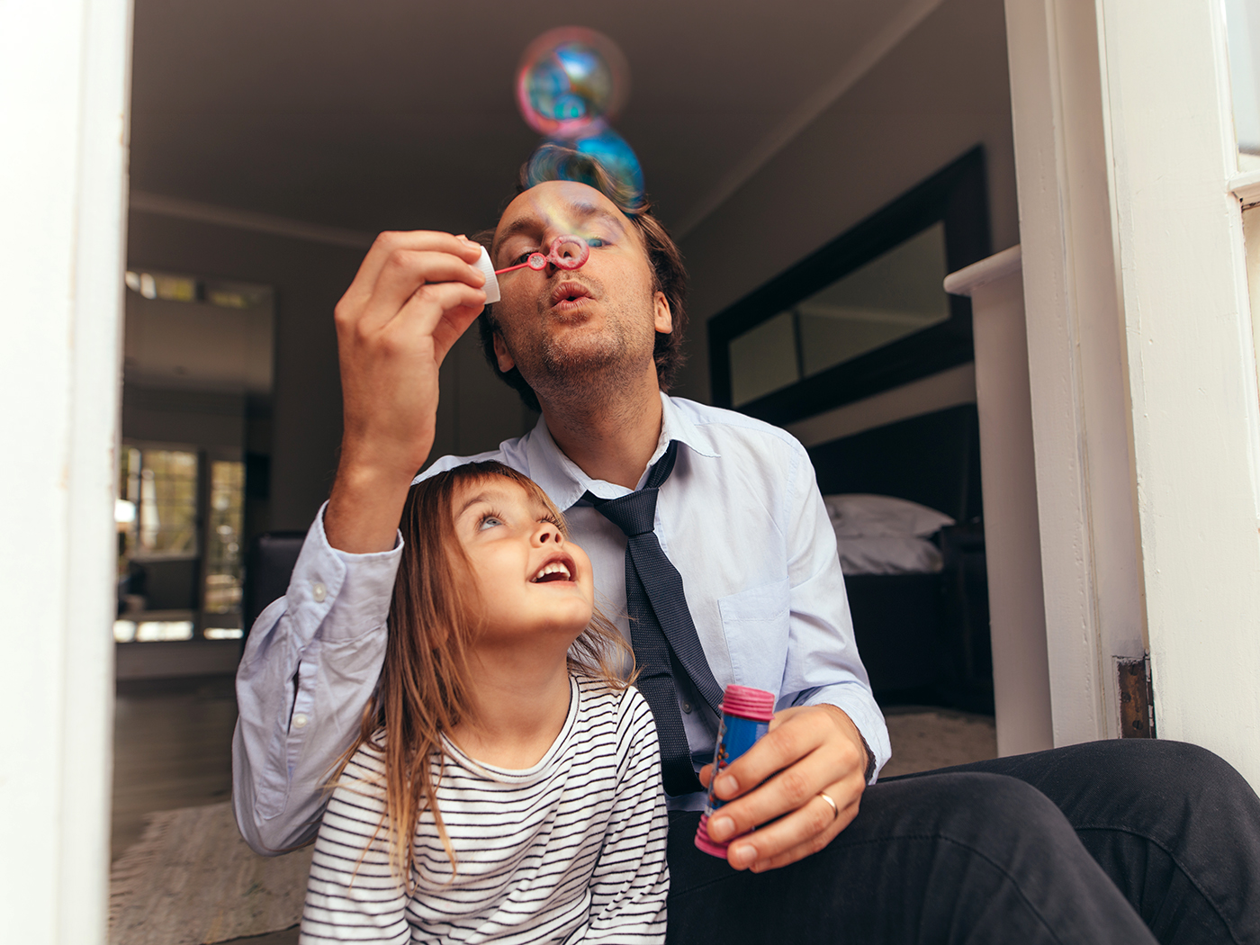 Padre e hija juegan con pompas de jabón en casa.