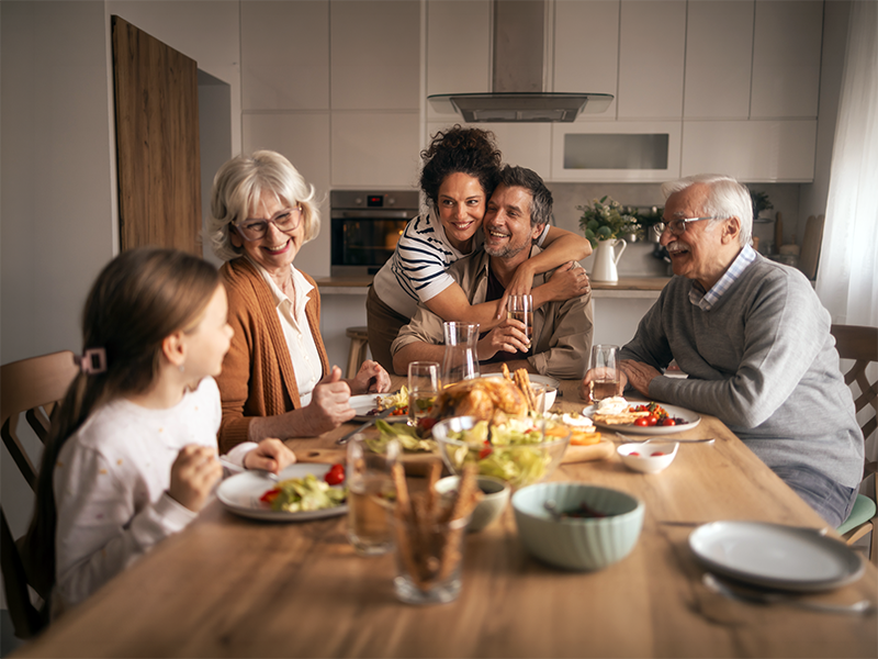 Familia multigeneracional compartiendo una comida en la mesa de la cocina.