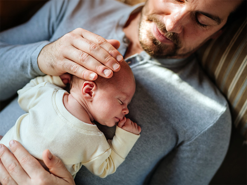 Recién nacido durmiendo en brazos de su padre.