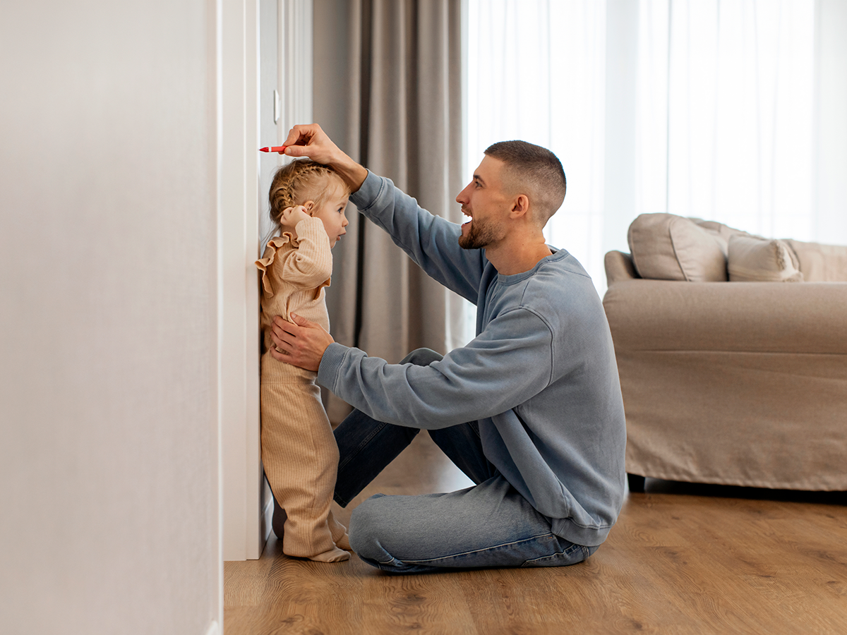 Padre mide con un rotulador en la pared a su hija.