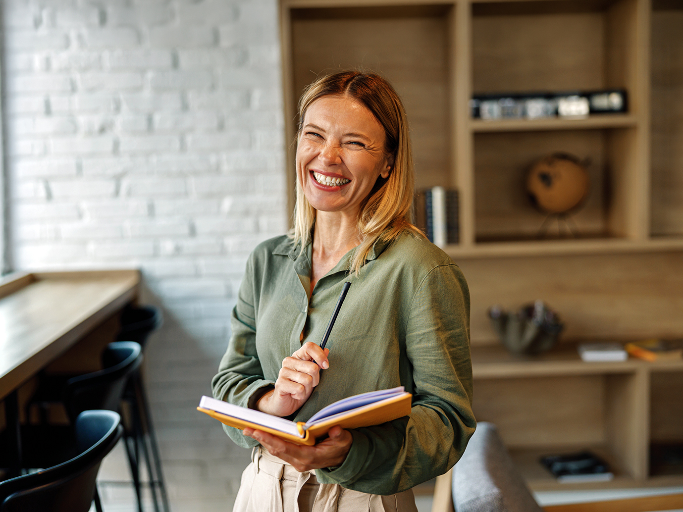 Emprendedora sonríe con su libreta en su estudio.