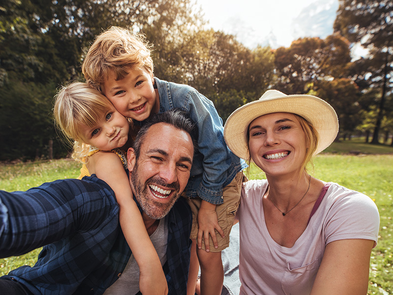 Familia sonriendo se hace un selfie en un parque