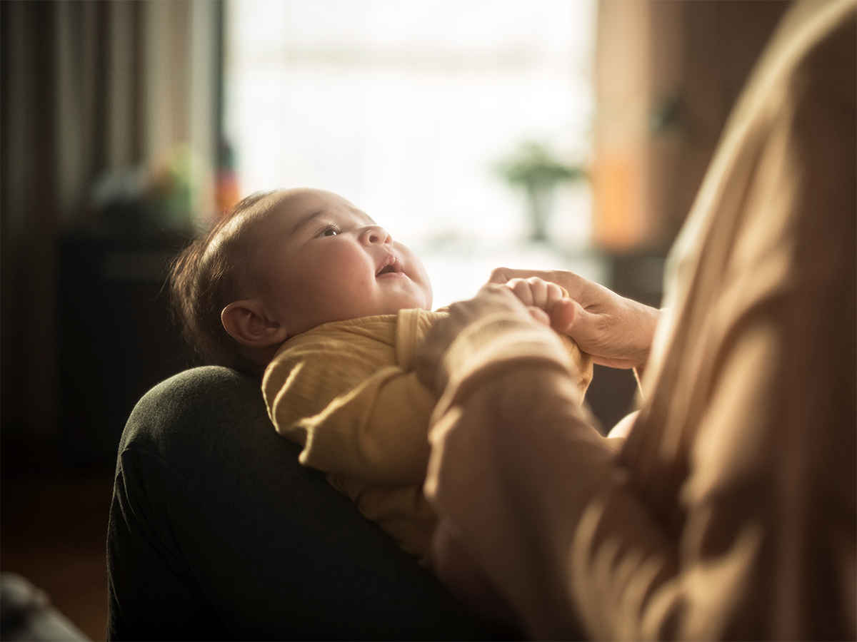 Una madre sostiene las manos de su bebé en el regazo.