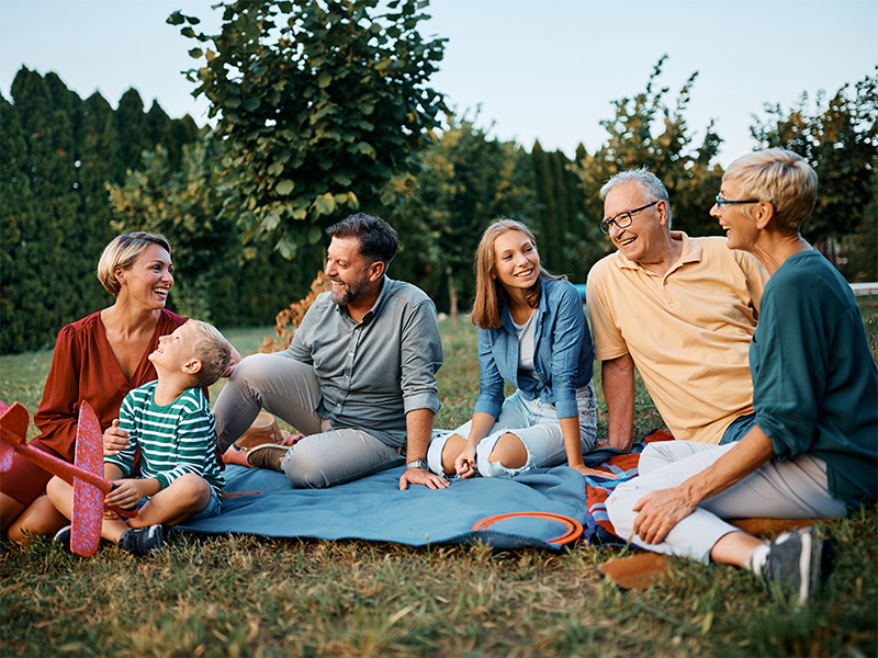 Abuelos, padres y nietos sentados juntos sobre el césped.