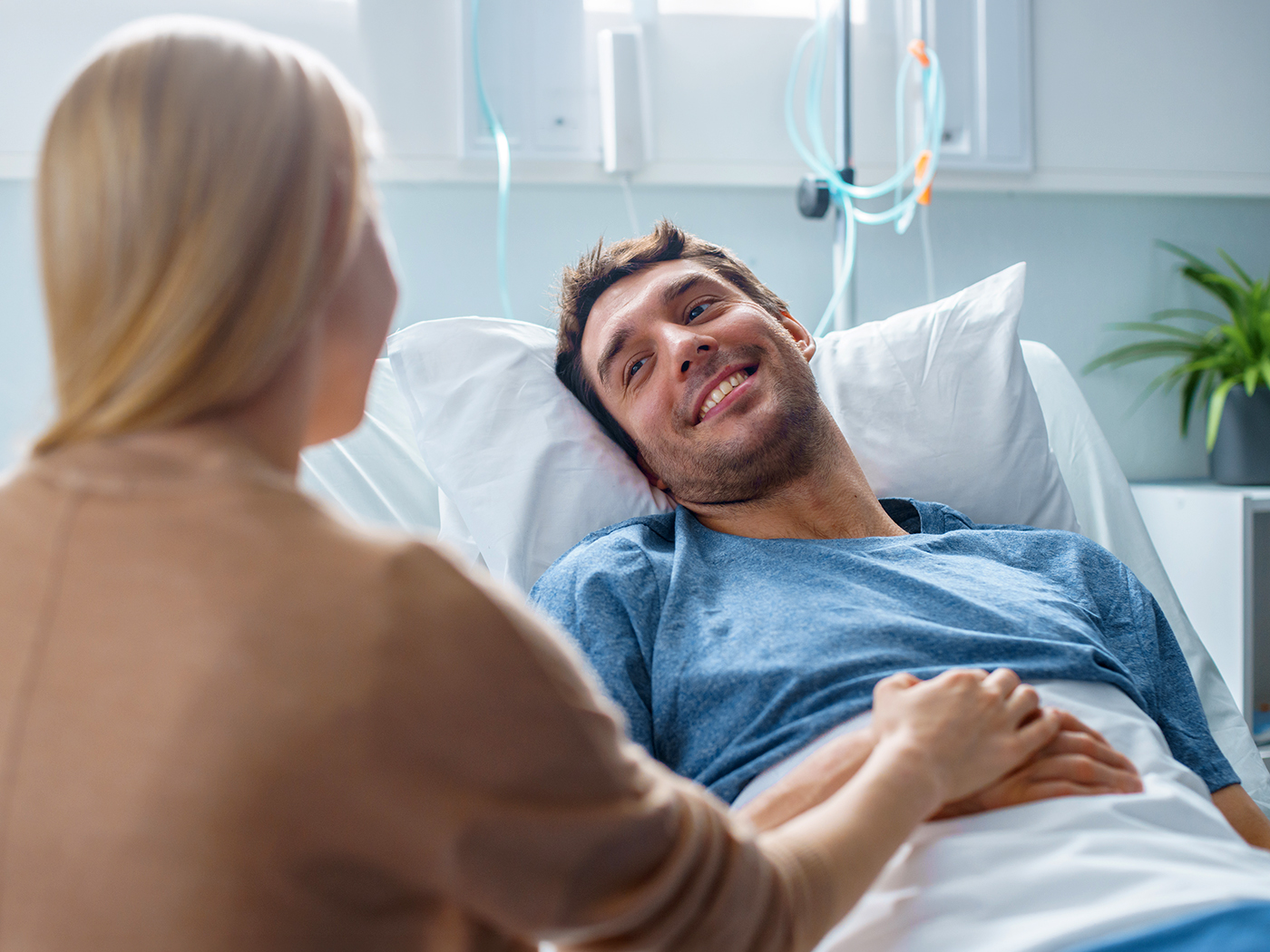 Pareja se coge de la mano junto a la cama del hospital.