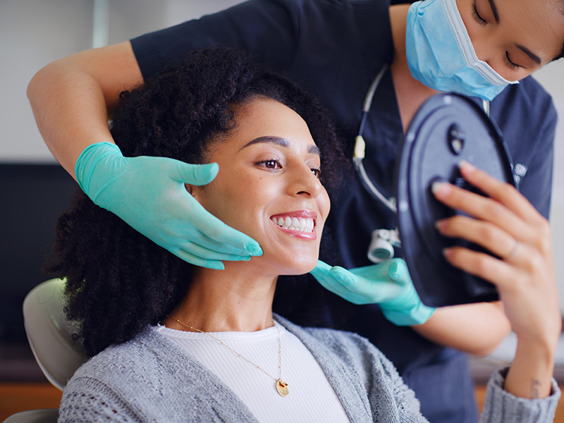 Paciente en consulta dental viéndose en el espejo junto a la odontóloga
