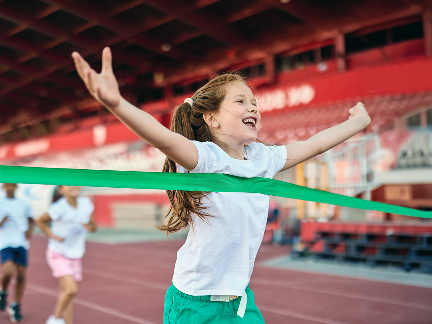 Niña celebra al cruzar la meta en la pista.