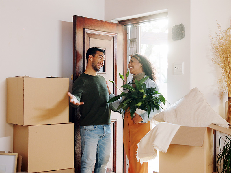 Dos personas entran en una casa con cajas de mudanza.