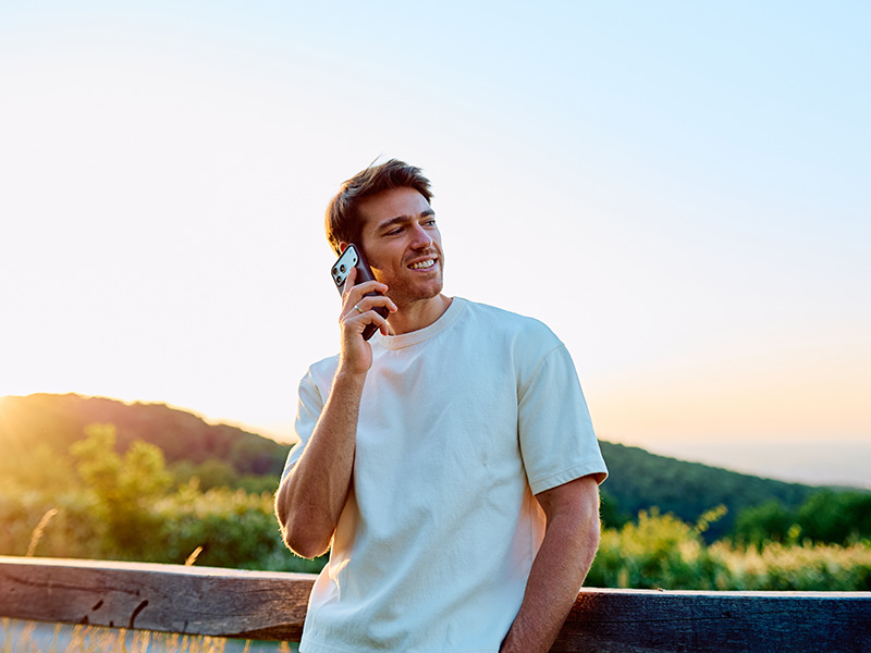  Hombre sonriente hablando por teléfono al aire libre.